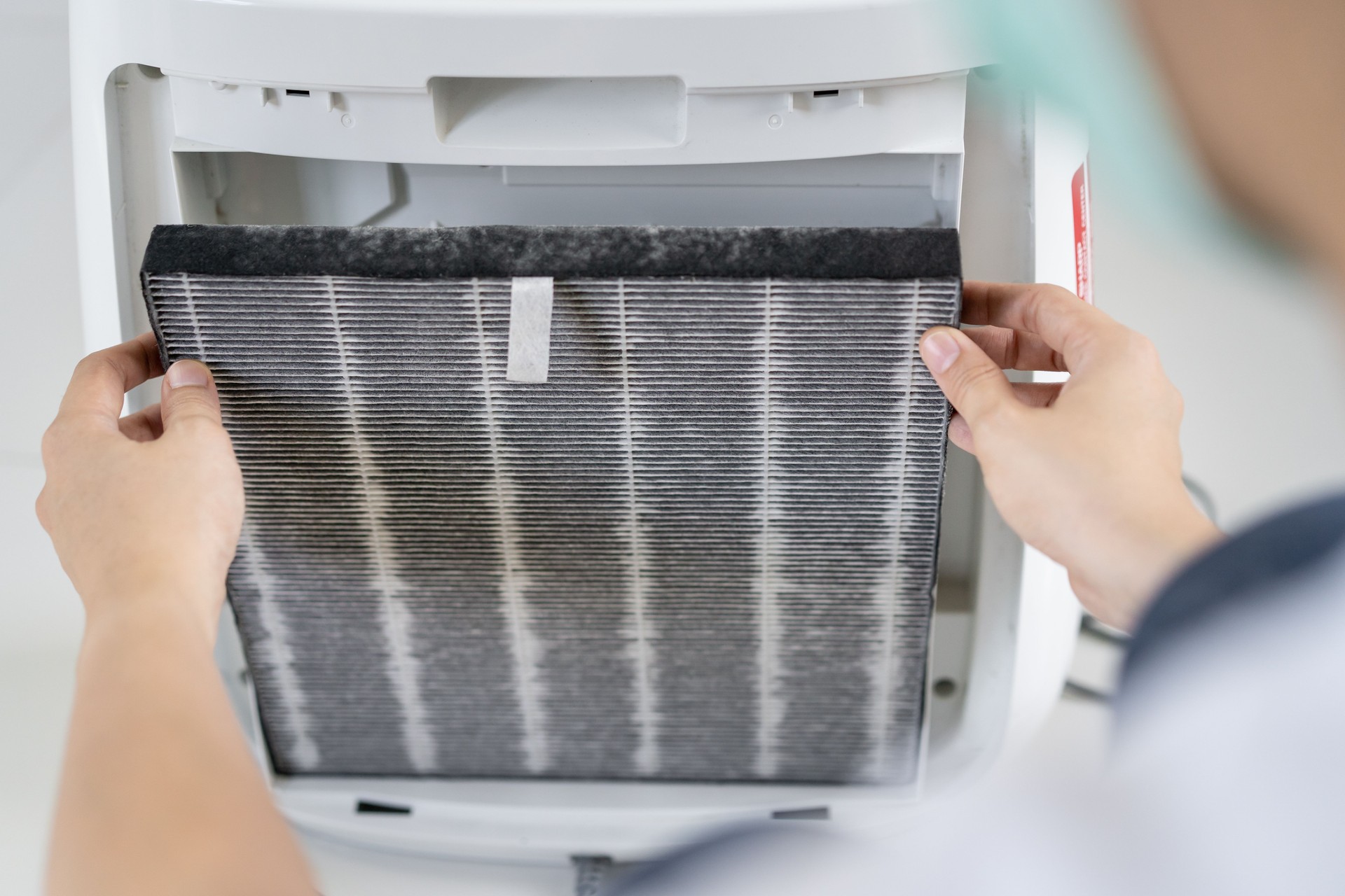 Woman changing an airpurifier filter.